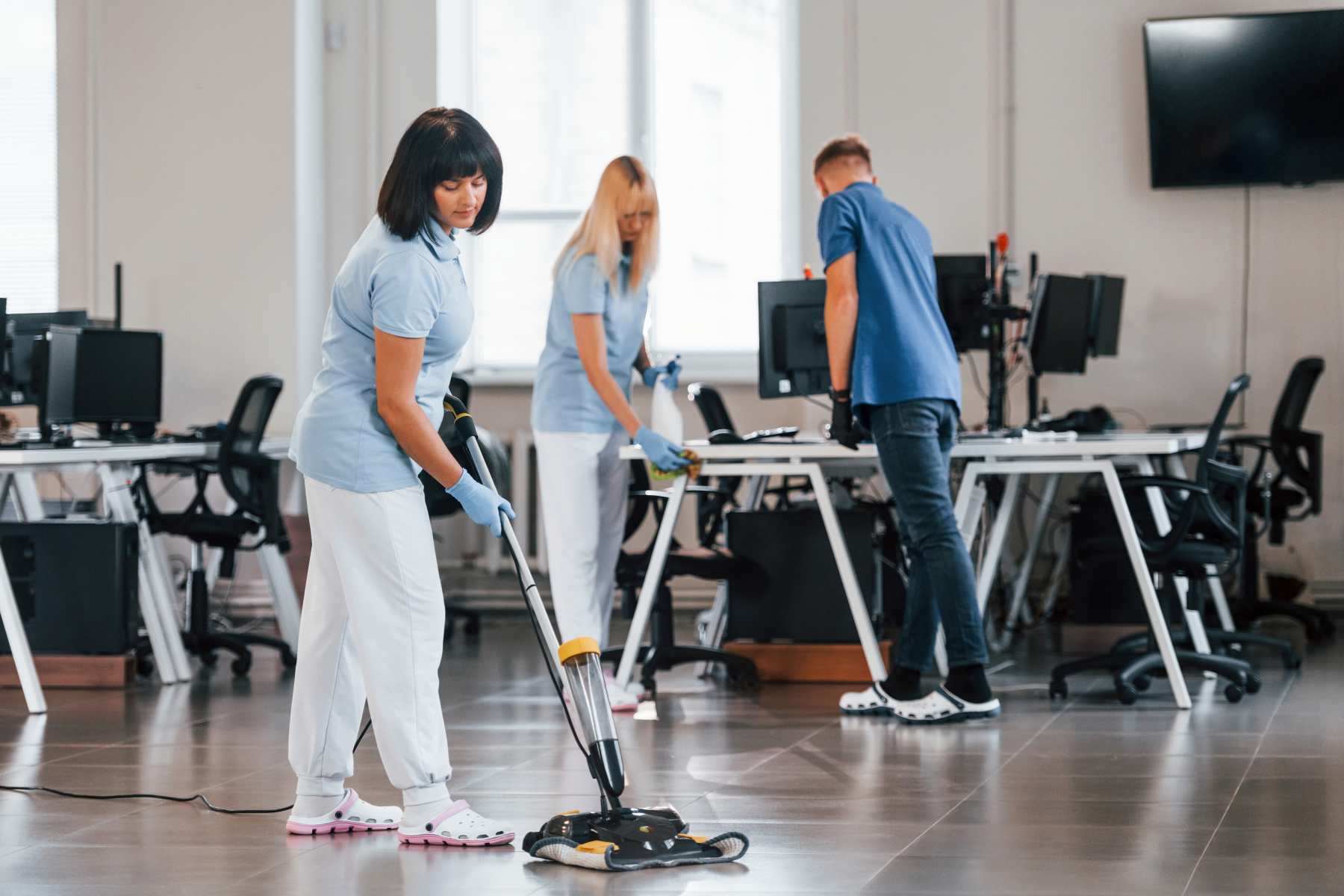 woman uses vacuum cleaner to clean workplace